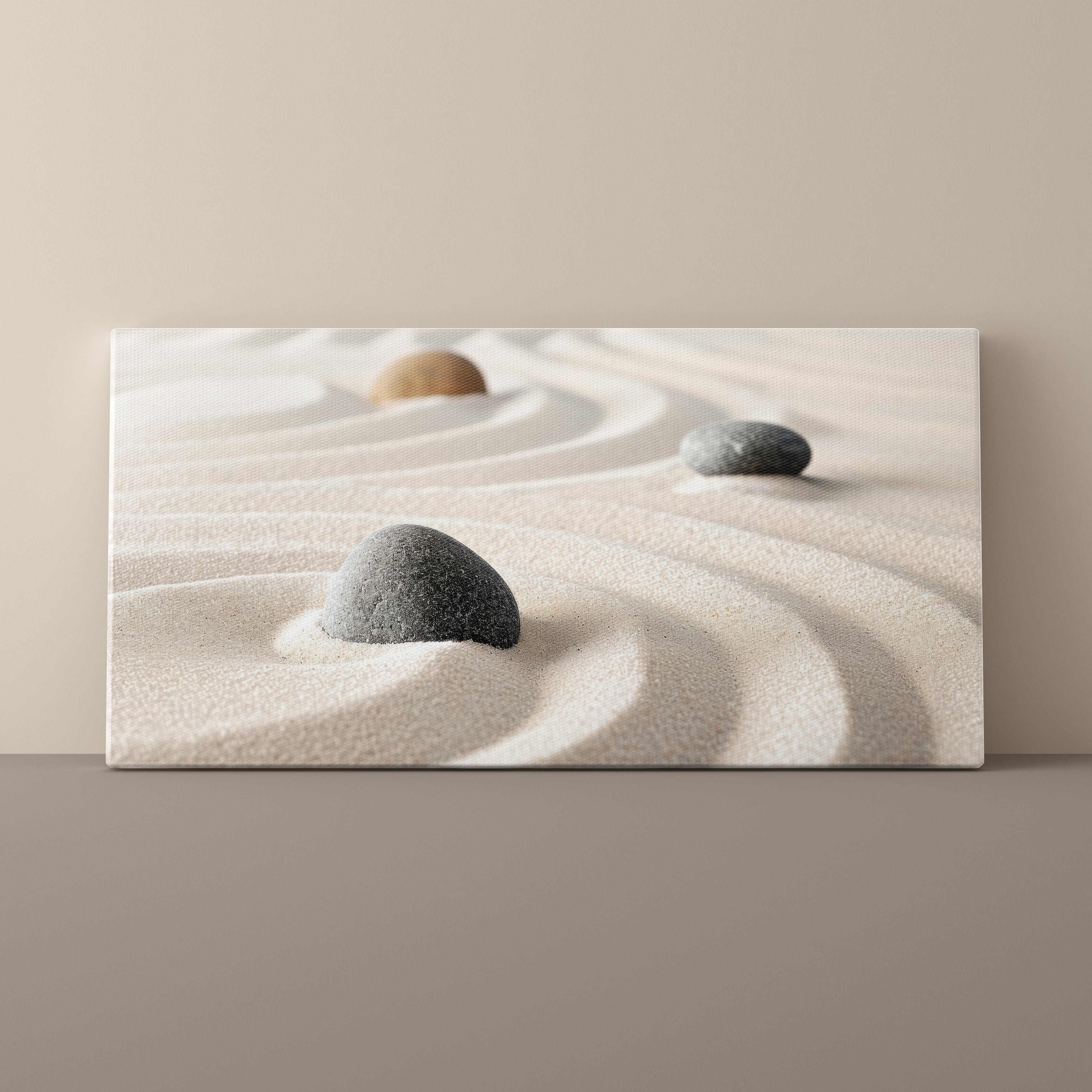 Canvas print of a minimalist scene with stones on sand against a beige wall.
