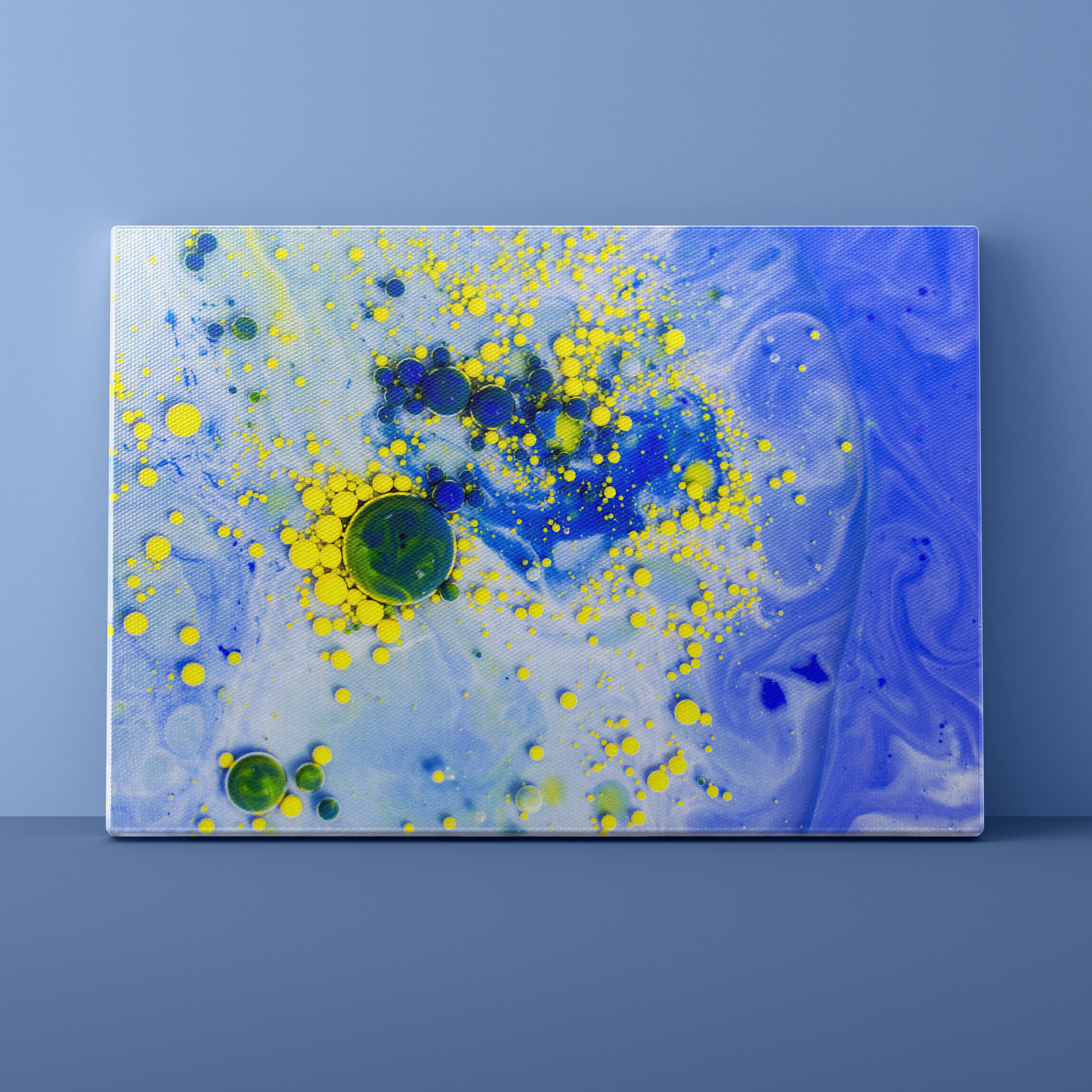 Abstract art canvas with blue, yellow, and green splashes on a blue background