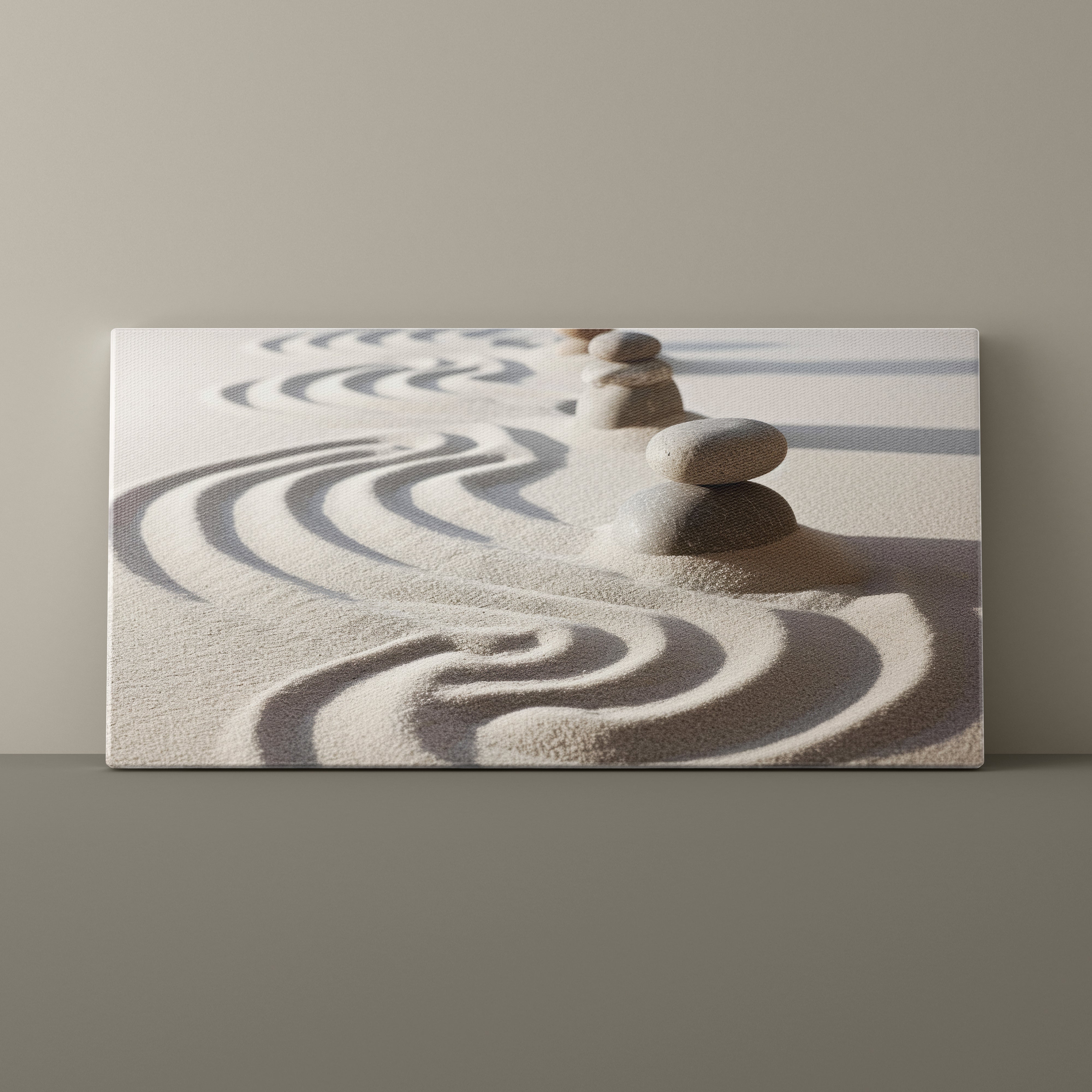 Canvas print of stacked stones on sand with wavy patterns against a beige wall.