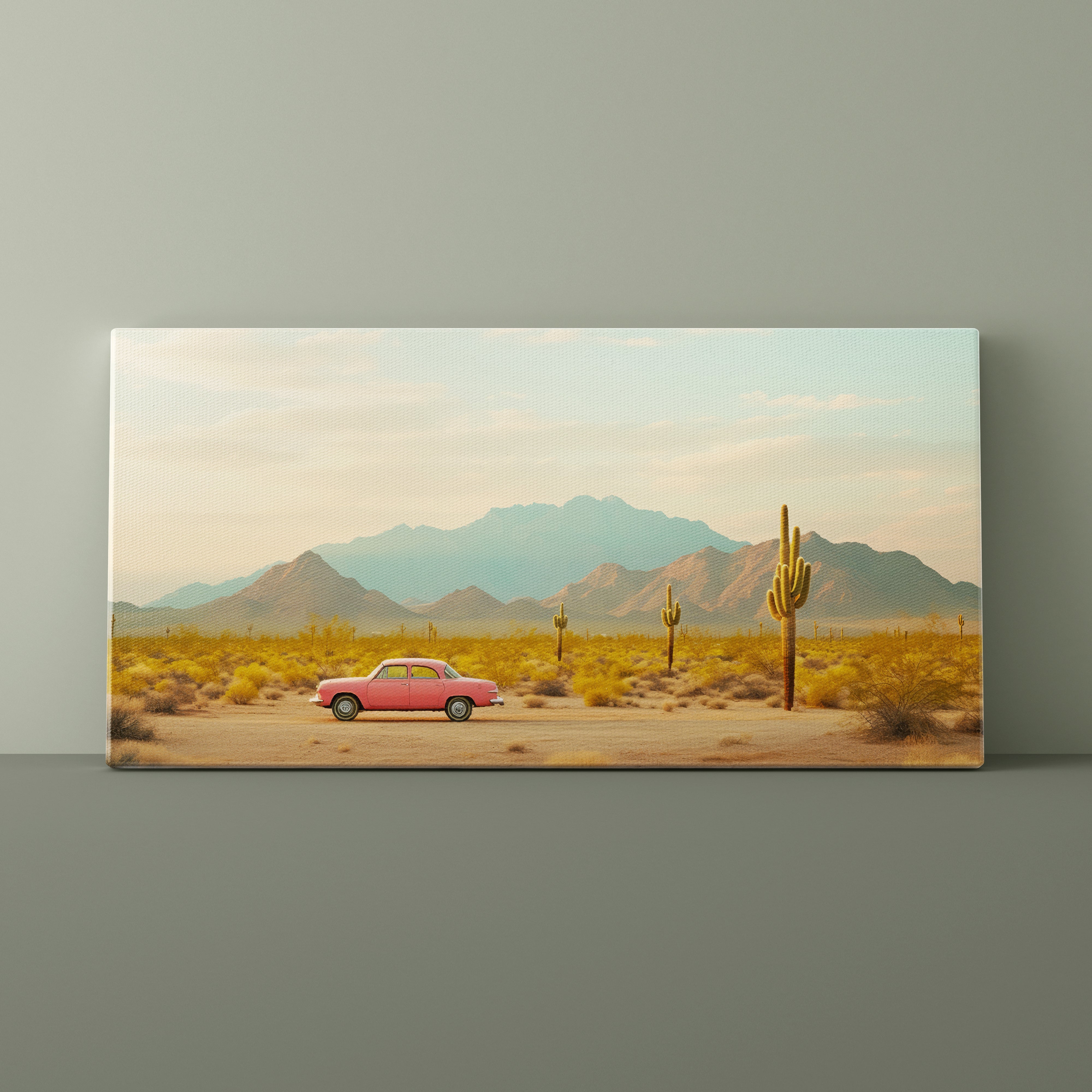 Desert landscape with a pink car and cacti on a canvas print against a gray wall.