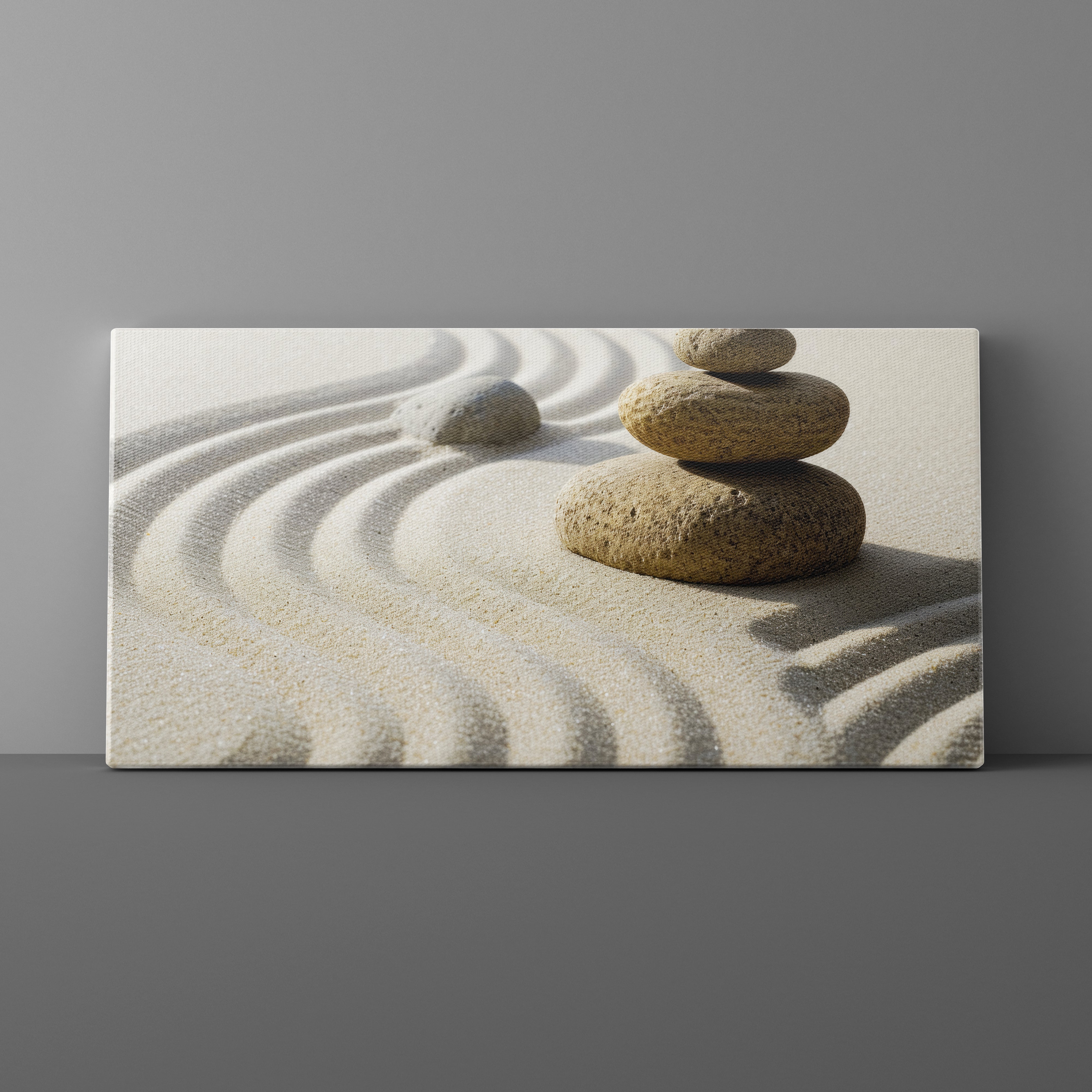Canvas print of stacked stones on sand with wavy lines against a gray background