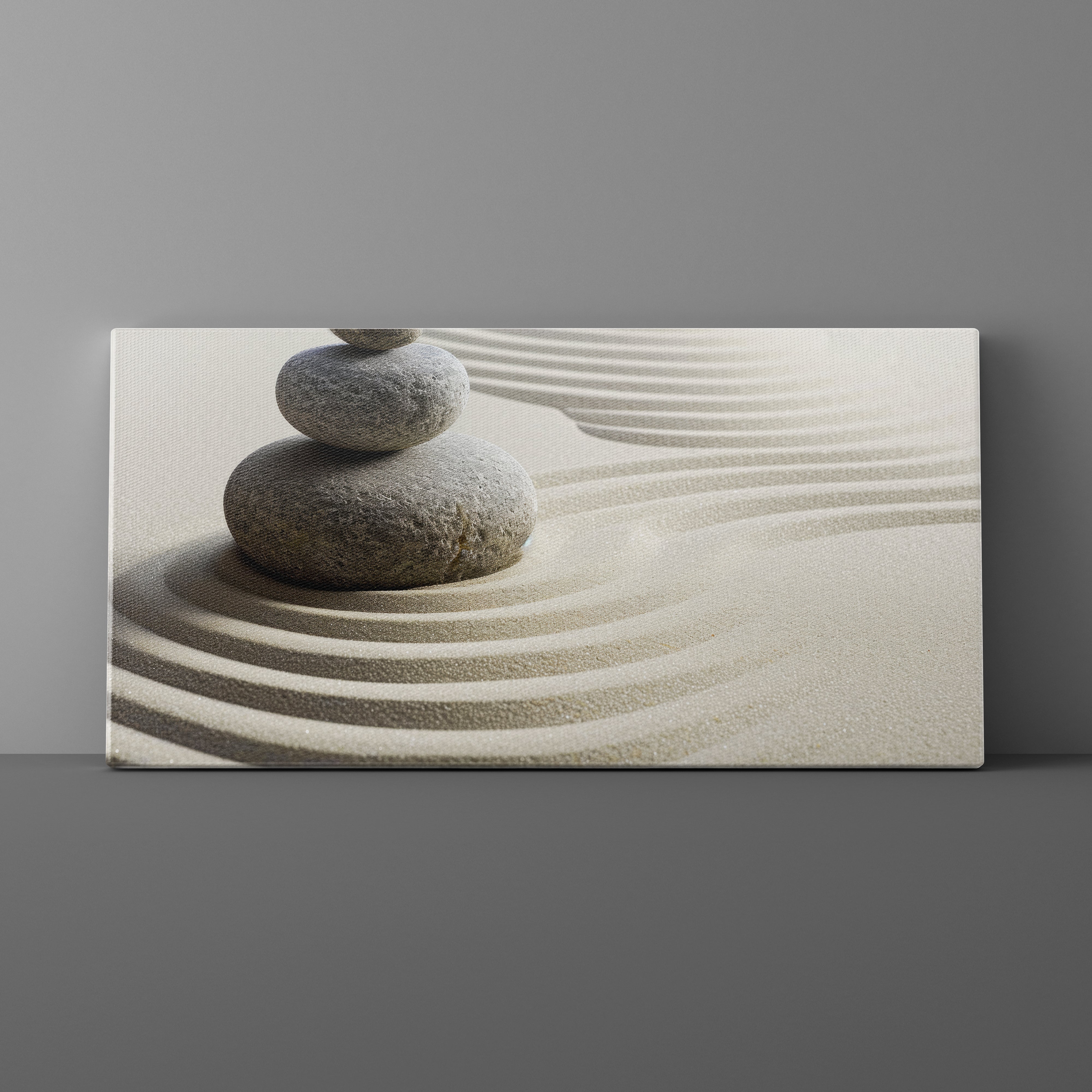 Canvas print of stacked stones on sand with wavy lines against a gray background