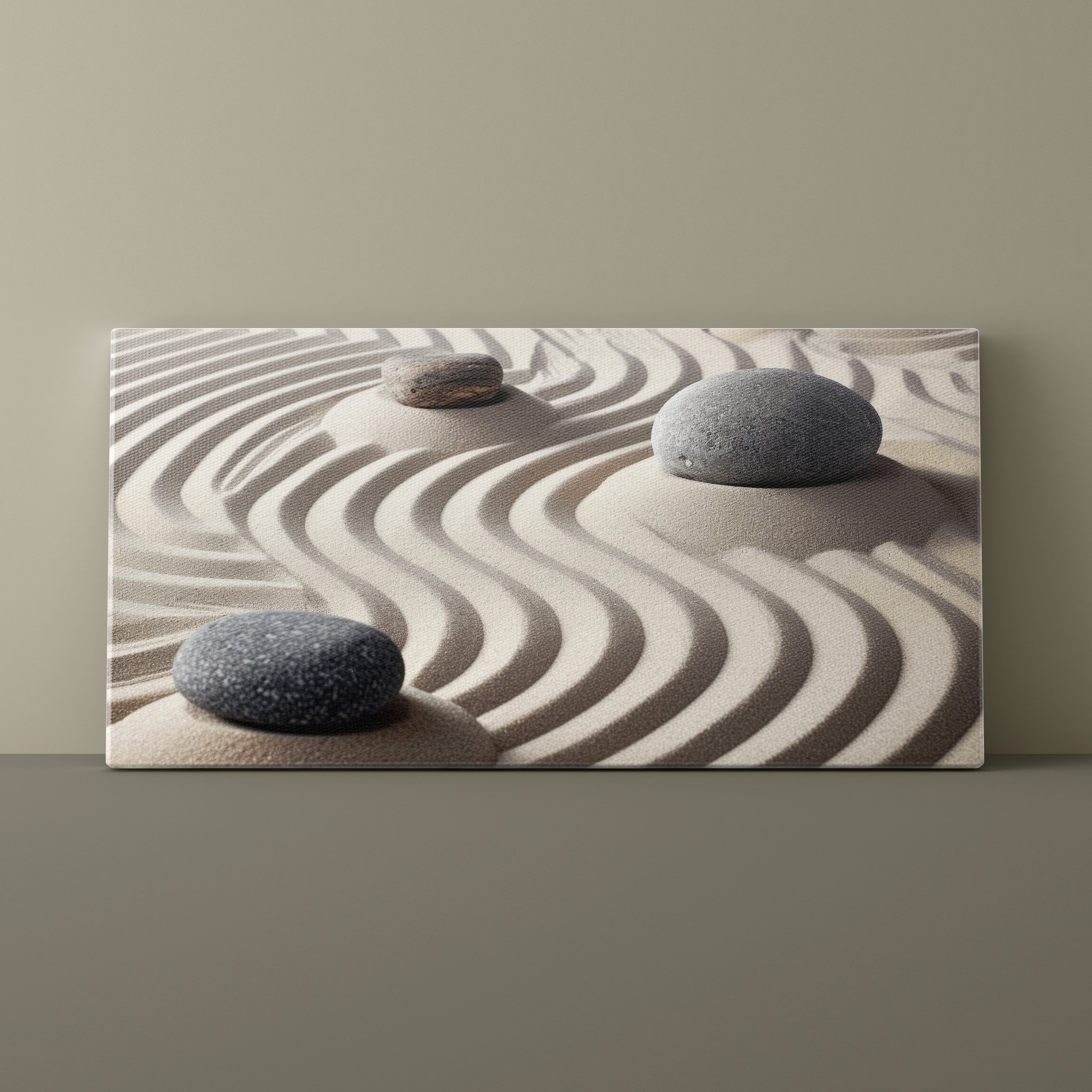 Canvas print of three stones on sand with wavy lines against a beige background
