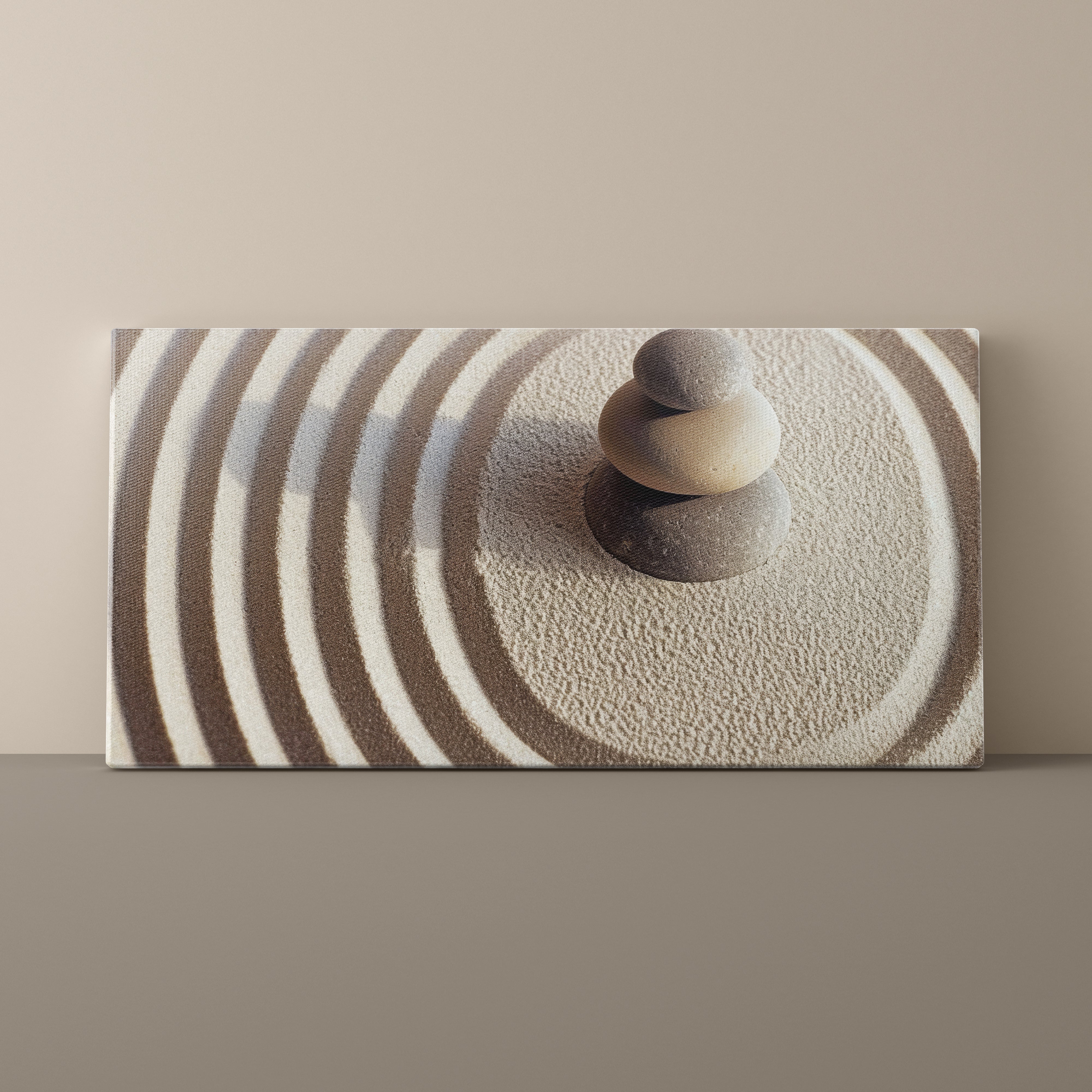 Canvas print of stacked stones on sand with concentric circle pattern
