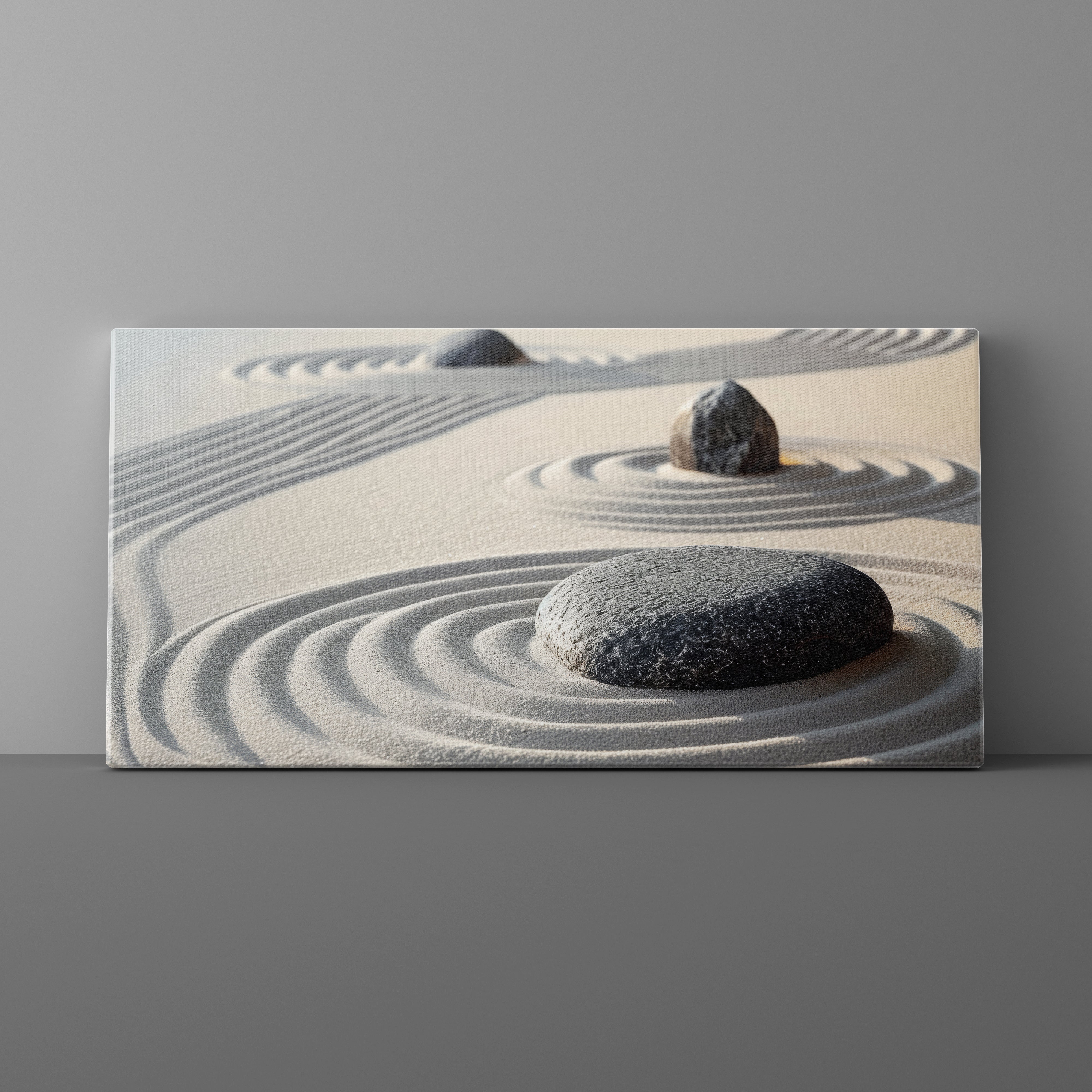 Canvas print of two stones on sand with concentric circles against a gray background